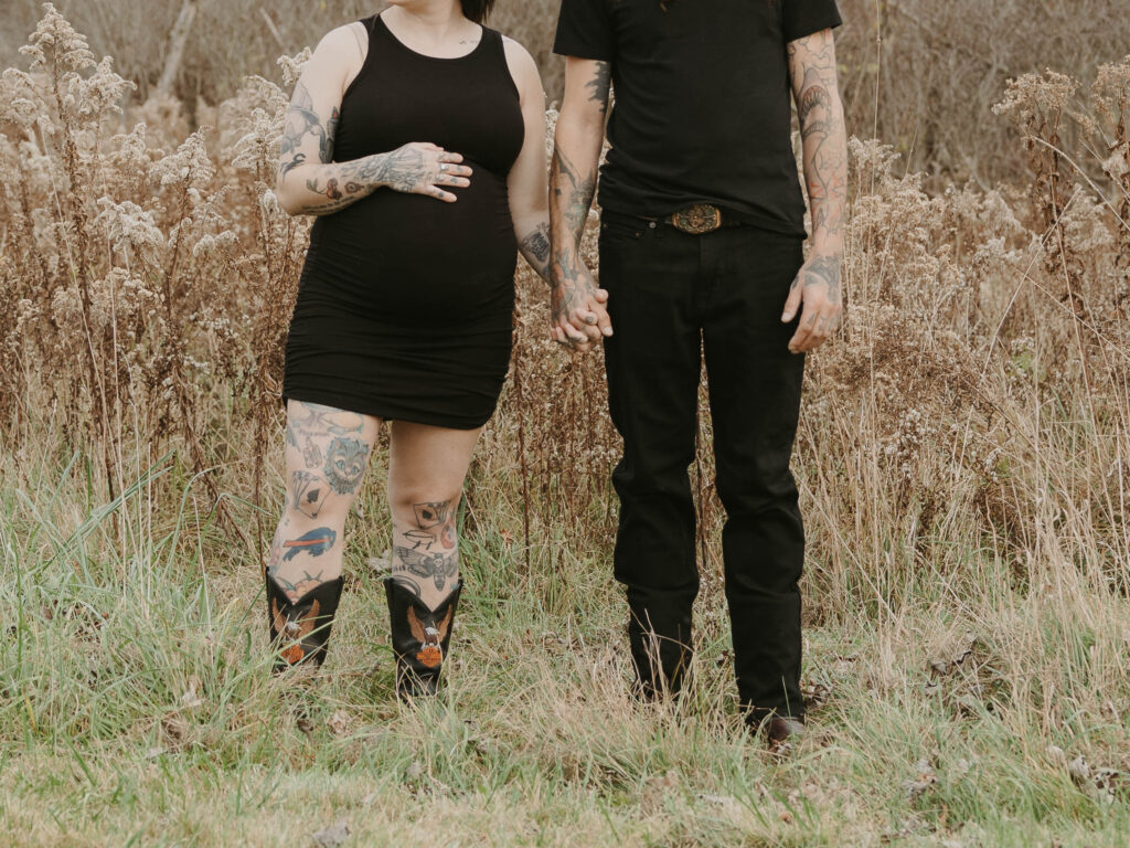 A close up image of 2 soon to be parents holding hands, while the mother holds her growing belly with the other hand. 