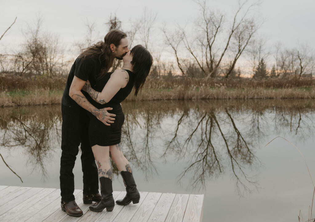 a couple kissing in front of a pond